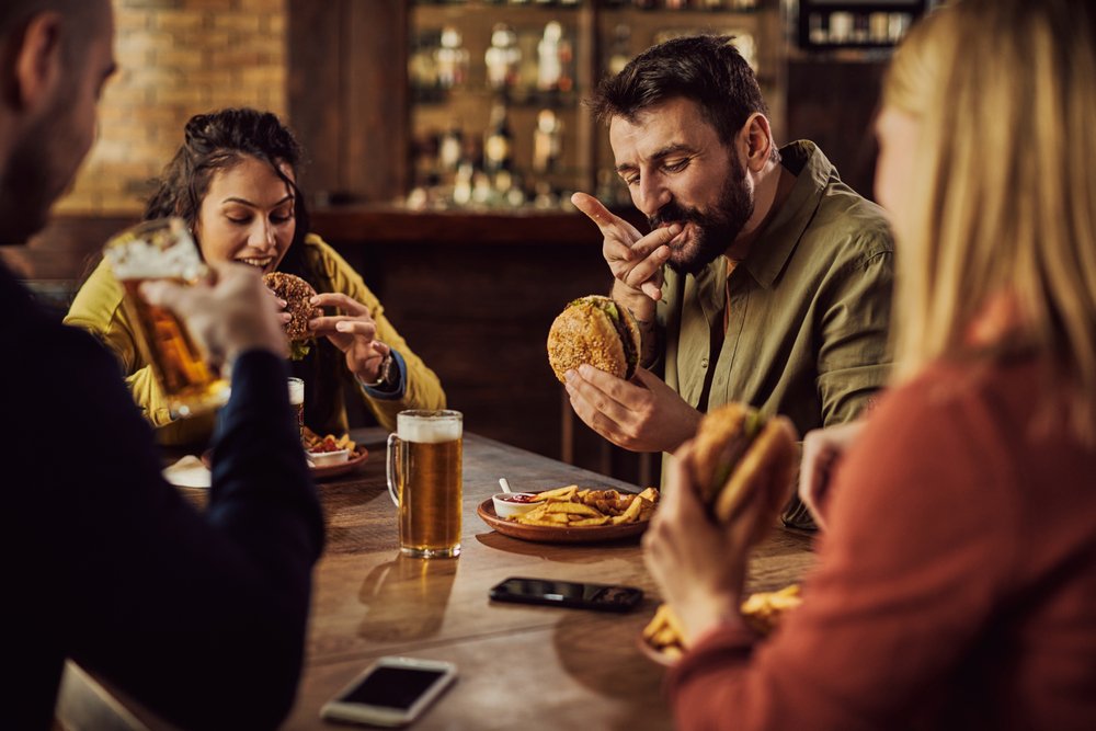 Group,Of,Friends,Drinking,Beer,And,Eating,Hamburgers,In,A